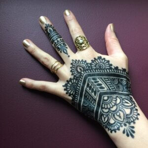 Jagua tattoo stain design on female hand with brass ring