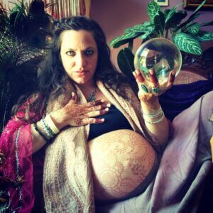 Pregnancy belly and hand henna tattoo on Turkish woman holding crystal ball