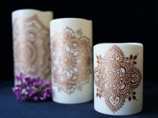 set of three led candles in varying size painted with mandalas in copper metallic paint